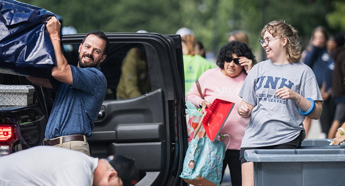 Adults help students unload their belongings from a car during move-in days