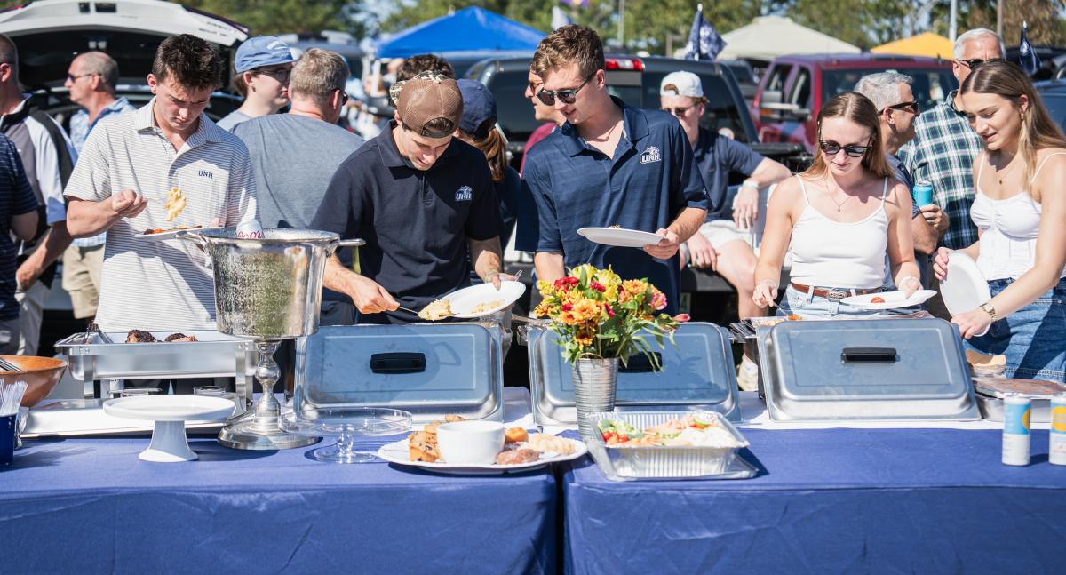 A line of people, many in UNH shirts, work through a buffet table