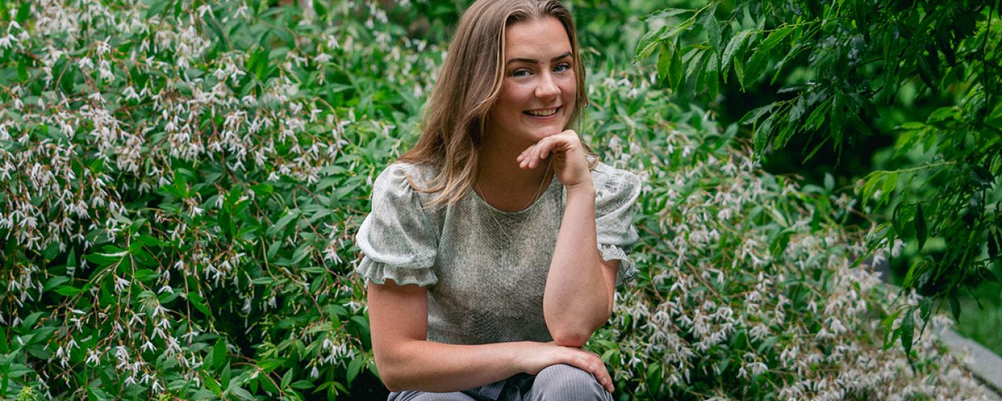 Clara Richards sits among the gardens outside Paul College.
