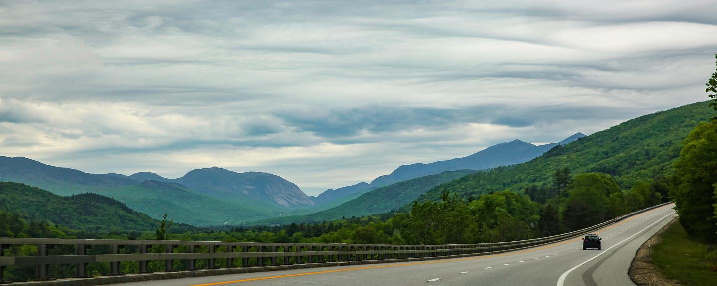 car driving on empty highway with mountains in backgroun