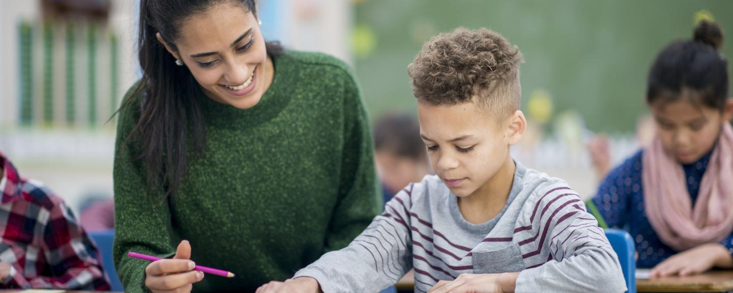 a female teacher working with a young student in a classroom