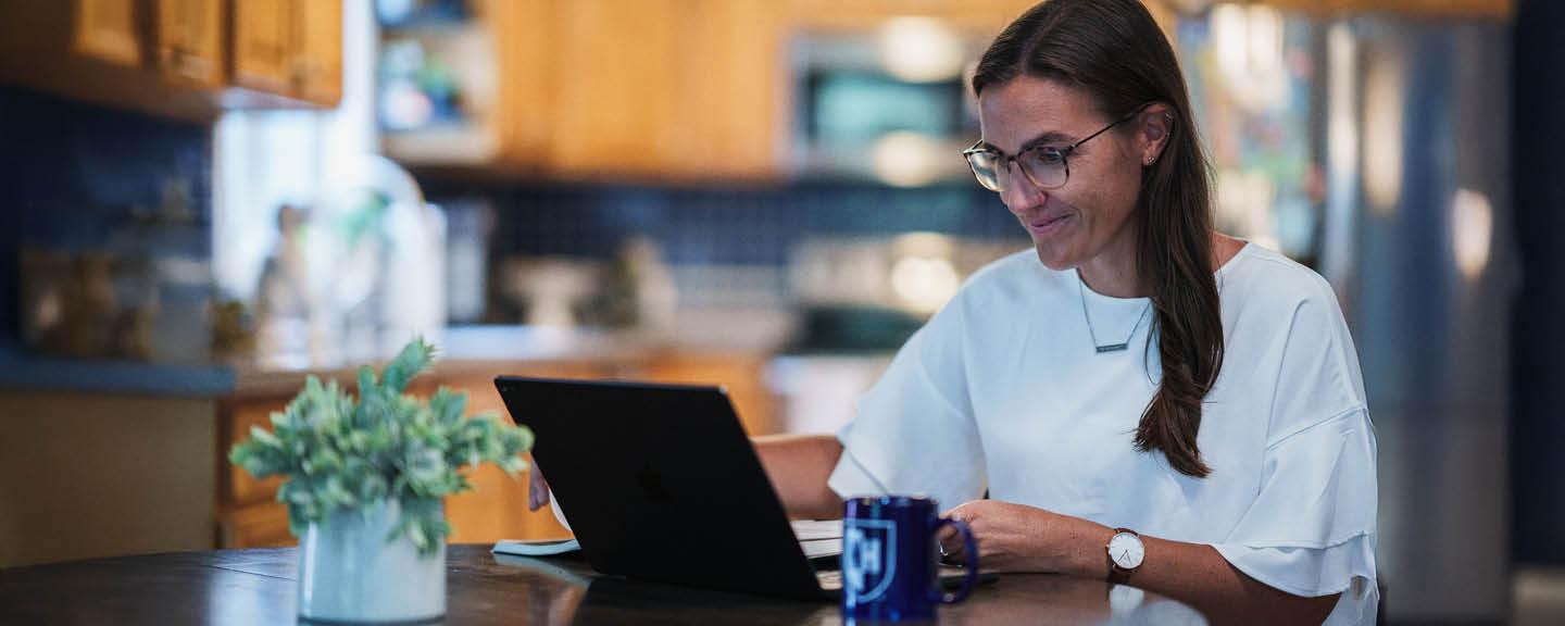 Girl with glasses on a tablet at the kitchen table