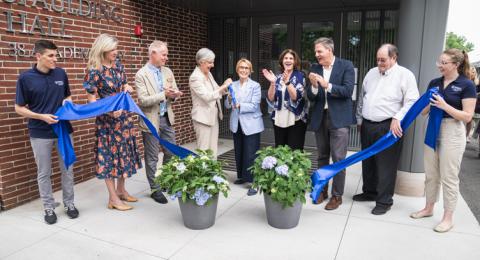 A crowd gathers around a ribbon for the official ribbon cutting ceremony at Spaulding Hall
