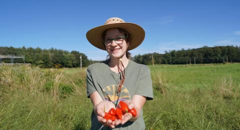 Student holding peppers in a field