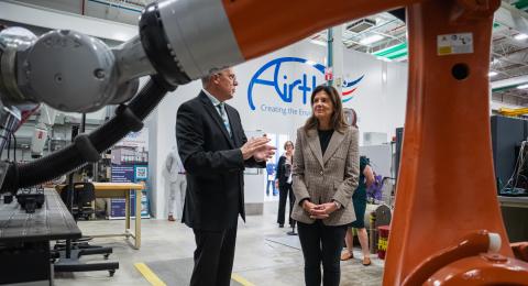 A man and a woman stand beneath a large robot talking