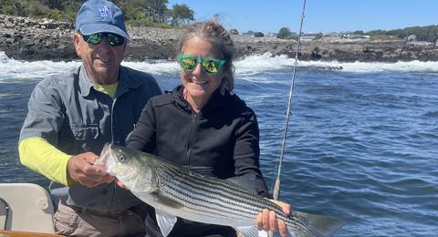Adrienne Kovach with large striped bass, fisherman Jim Smith 