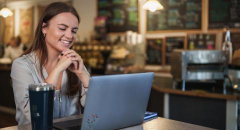 A woman looks at a computer on a table in a coffee shop