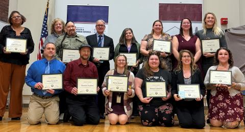 A group of people holding certificates to celebrate graduation from the FELEIA Academy gather for a photo