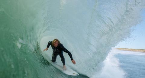 Image from inside a wave of a surfer ducking low on his board