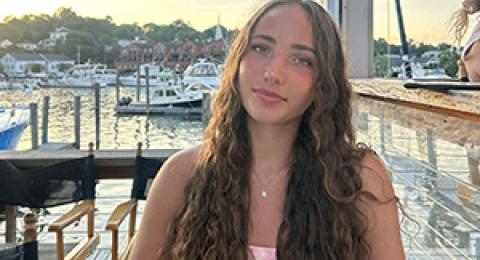 person outside with a dock, boats, and water in the background