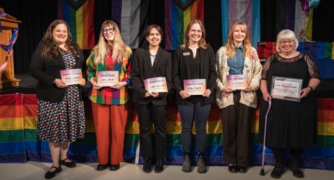 Six Bill Kidder Award recipients pose together holding their awards on stage