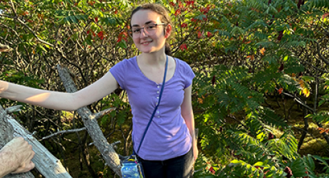 UNH student Jes Calarese standing outside with trees in the background
