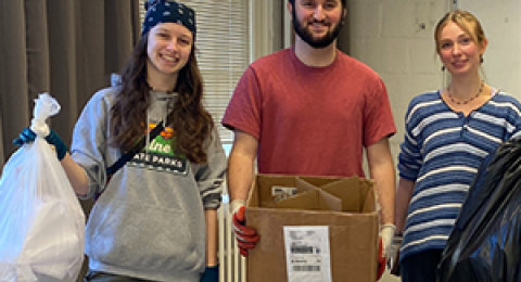 Three students holding trash bags