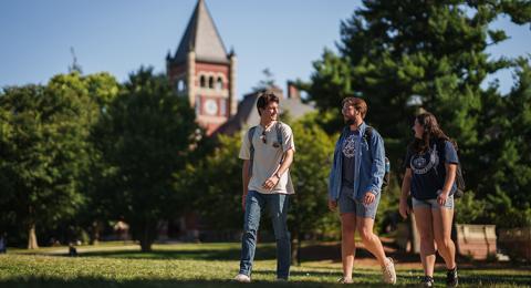 Three students walk on campus with Thompson Hall in the background