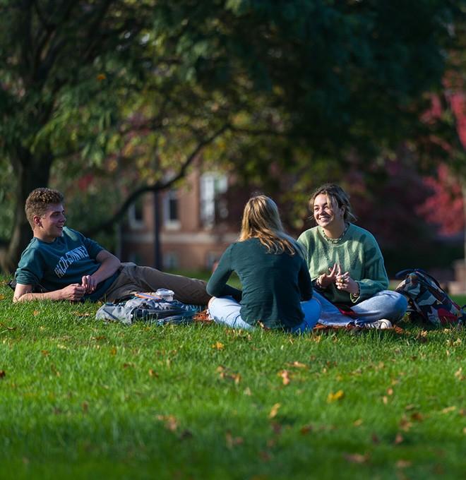Three students laying in the grass outside
