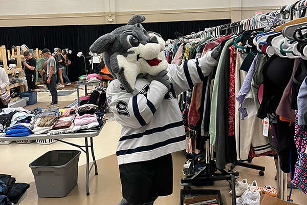 Wildcat mascot looks at clothing on a rack
