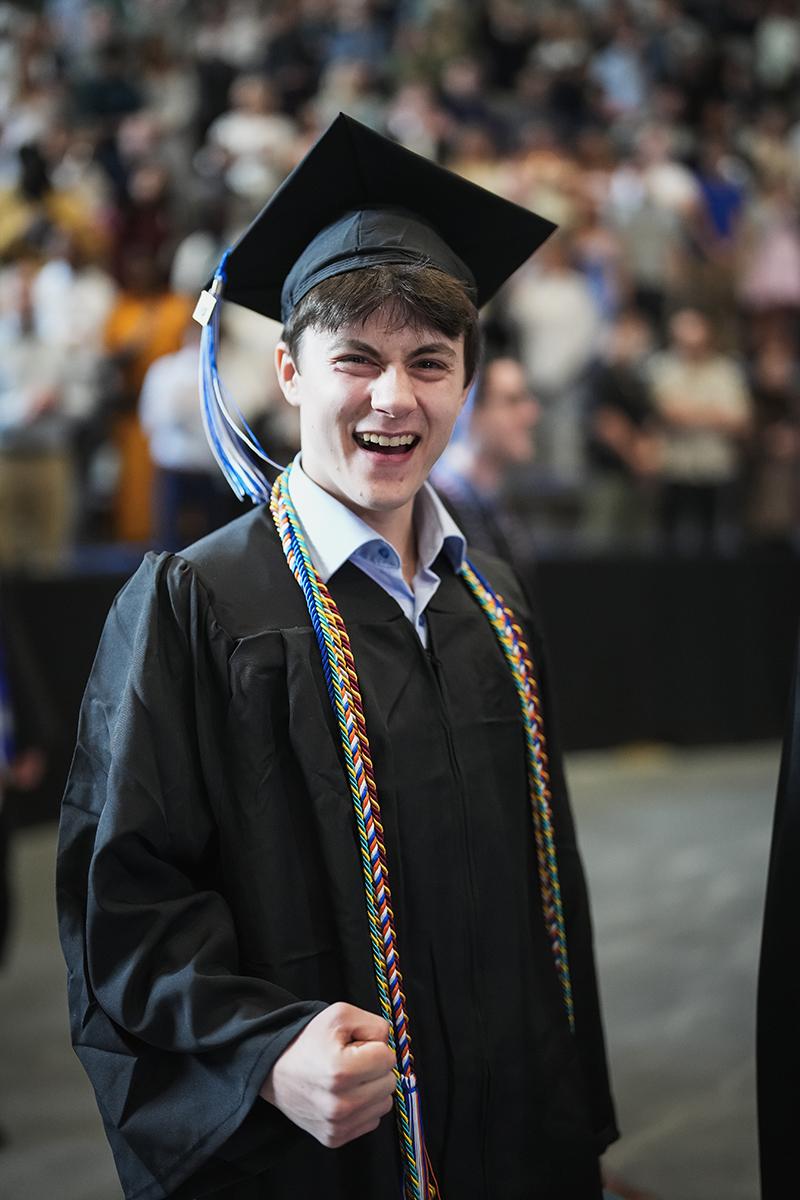 A male graduate pumps his first walking into commencement