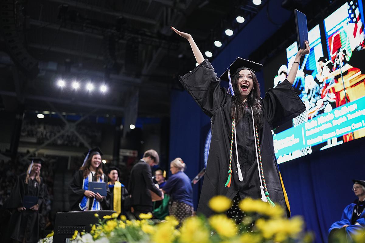 A woman graduate walks across stage at commencement