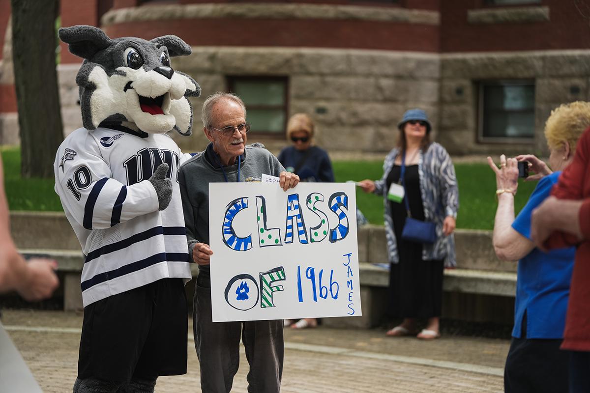 A member of the class of 1966 takes a photo with Wild E Cat at reunion