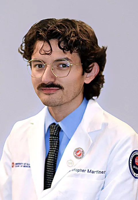 UNH alumni Christopher Martinez poses in his medical school white coat