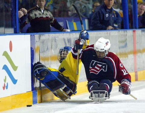 Hockey player checking another player into a wall