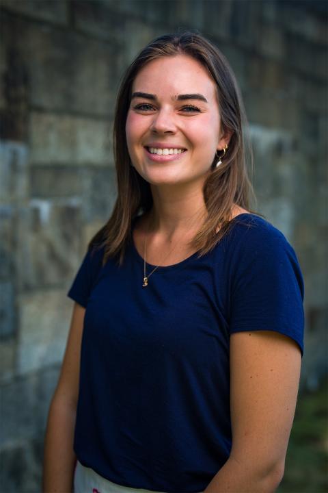 Master of Science in Nutrition student Maya Stadler. Maya has white skin and brown hair, her hair cropped just below shoulder length. She wears a dark-blue top.