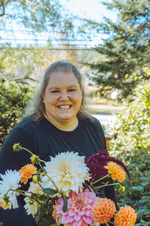 A smiling woman holds a bouquet of flowers.