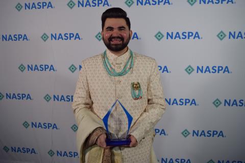 Yashwant Prakash Vyas holds a glass award in front of a NASPA backdrop