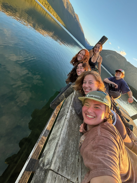 Group of UNH students taking a selfie while laying on a dock overlooking a lake