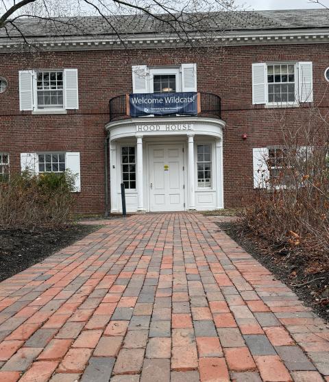 A brick walkway leads up to the entrance of Hood House, a brick building with a white entry