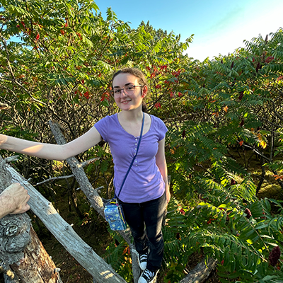 UNH student Jes Calarese standing outside with trees in the background