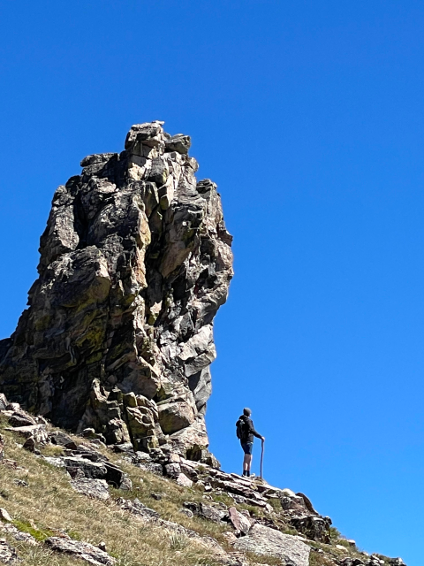 person hiking next to a large rock formation
