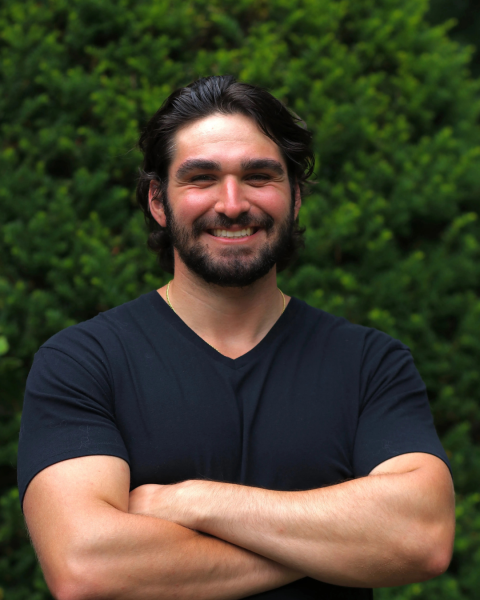 person smiling with bushes in the background