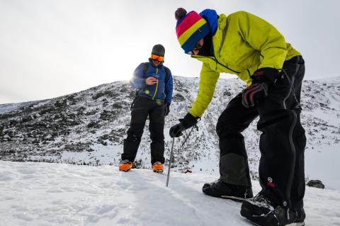 Two people monitor snow in the mountains