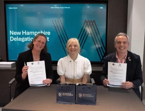 Three people smile at the cameras holding paper at the signing of the agreement between UNH and Space Hub Yorkshire