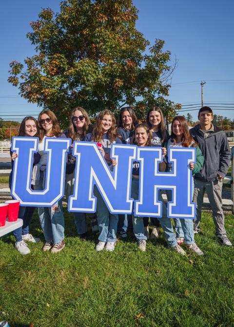 group of students outside with UNH letter sign