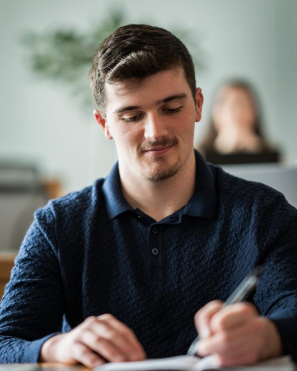 UNH student taking notes in class