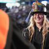 A female graduate wearing a fireman's helmet shakes hands as she accepts her diploma