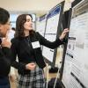 Female student points to a poster while explaining its content to a male to her left