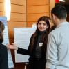 A woman points to a poster while speaking to a man and a woman