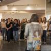 A group of onlookers listens to a presentation in an art gallery