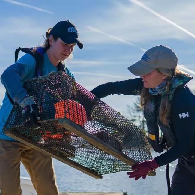 Two students holding a crab trap